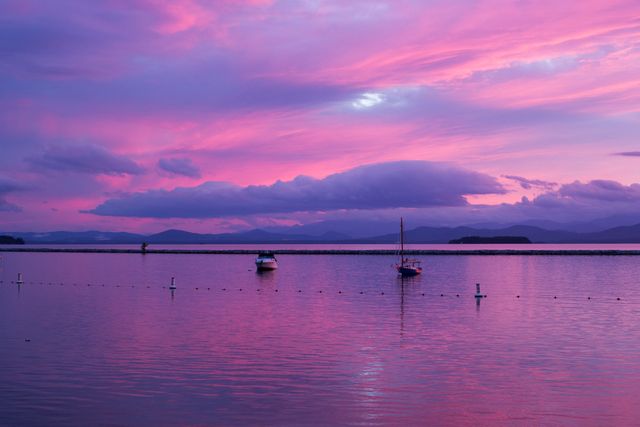 This beautiful image of a lake at sunset with two boats reflecting on the water under a purple sky and fluffy clouds creates a tranquil and serene atmosphere. Ideal for use in travel brochures, nature photography galleries, relaxation and wellness content, backgrounds for websites and social media posts celebrating natural beauty.