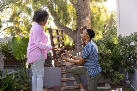 African american man kneeling proposing engagement in lush backyard garden romantic proposal moment