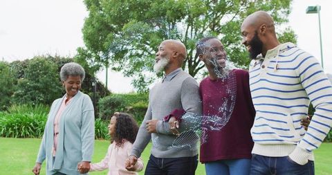 Multigenerational family walking hand in hand through green park with AR overlay