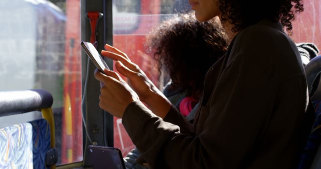 Parent traveling with child during daytime using a tablet on public transportation. Ideal for concepts of mobile technology, family travel, commuting, or public transport scenarios.