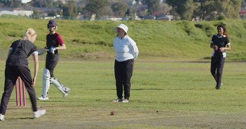 Women Engaged in Cricket Match on Lush Green Field