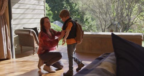 Mother Helping Son with Backpack in Sunlit Living Room