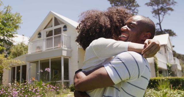 This image shows a father and daughter hugging and smiling in front of their home, conveying joy and happiness. It can be used for family-related content, real estate promotions, or adverts emphasizing positive relationships and well-being.