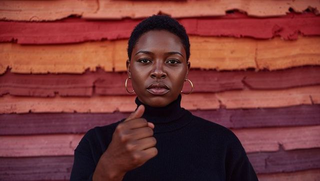 Confident woman extending thumb toward camera against weathered colorful urban wood panels