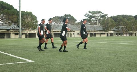 Soccer players in black uniforms warming up on field