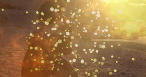 Pregnant Woman Kneeling on Sandy Beach at Sunset with Lens Flare