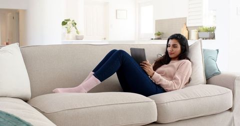 Woman Relaxing on Sofa with Tablet in Modern Minimalist Living Room