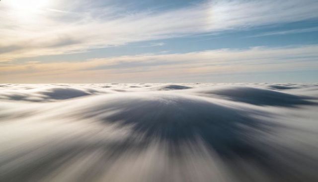 Gliding over stratocumulus waves under pastel sunrise sky with streaked motion and horizon
