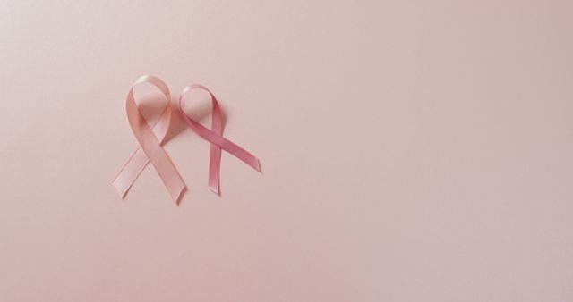 Beautiful composition featuring two pink ribbons symbolizing breast cancer awareness on a light pink background. Ideal for promoting breast cancer awareness campaigns, healthcare and support initiatives, charity events, medical prevention programs, and educational materials. The minimalistic design with copy space is perfect for adding text or logos.