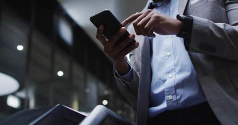 Businessman Tapping Smartphone at Office Escalator