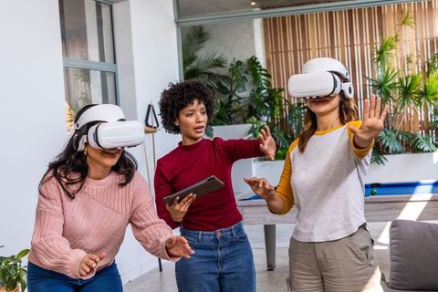 Diverse women using vr headsets in modern office lounge for collaborative vr training