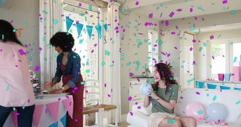 Friends celebrating at home with balloons, confetti, bunting in sunlit living room
