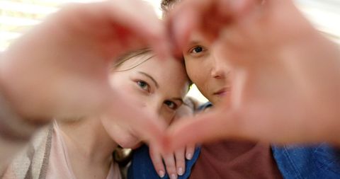 Smiling Couple Making Heart Shape with Hands Outdoors