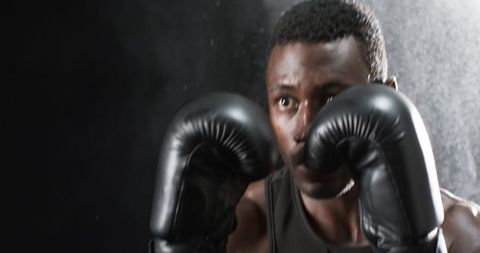 Determined boxer in gloves holding defensive stance during training