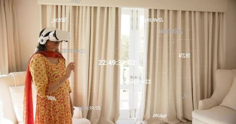 Indian woman wearing kurta dupatta using vr headset viewing holographic data at home