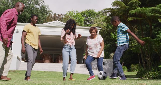 Family enjoying quality time playing soccer in backyard. Great for concepts of togetherness, leisure, sports, multi-generational activities, and outdoor play. Perfect for advertisements promoting family wellness, recreation, and happy lifestyles.