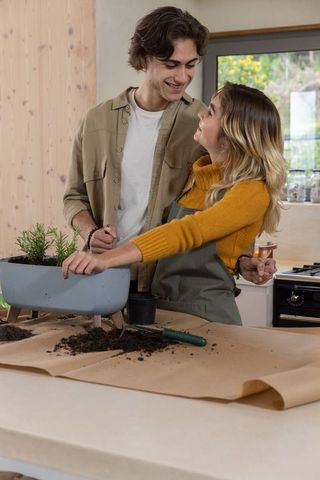 Couple gardening indoor herbs at kitchen counter