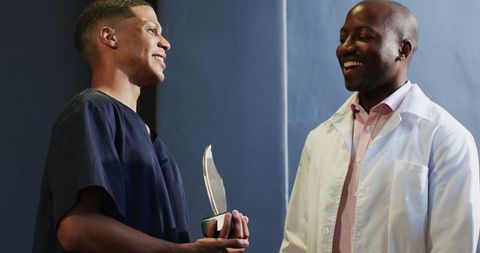 Excited professionals celebrating recognition with award in office