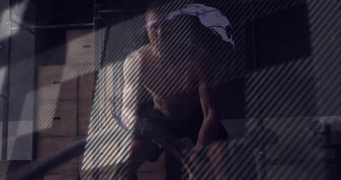 Shirtless man pulling battle ropes in industrial gym during intense strength training