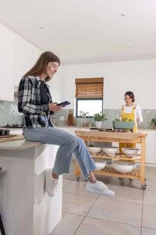 Young friends cooking together in bright kitchen, preparing casual salad among plants