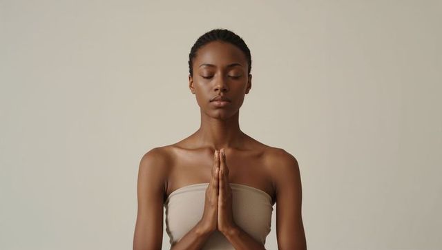 Minimalist serene woman meditating with hands in prayer pose on beige background