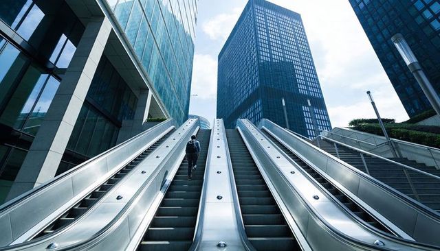 Commuter Ascending Central Outdoor Escalator Between Glass Skyscrapers Reflecting City Light