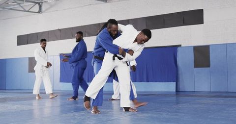 African american men practicing judo throws in training hall