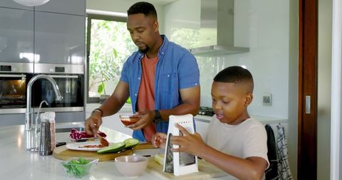 African American Father and Son Cooking Pizza Together at Home