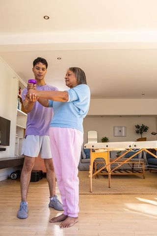 Senior Woman Exercising with Personal Trainer at Home for Physical Wellness