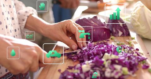 Chopping purple cabbage on wooden board showing sustainability icons at community cooking