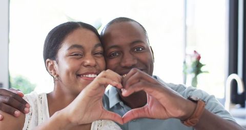 Happy Couple Making Heart Gesture in Warm Loving Moment