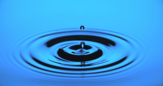 A single water droplet creates ripples on a blue surface - Download Free Stock Photos Pikwizard.com