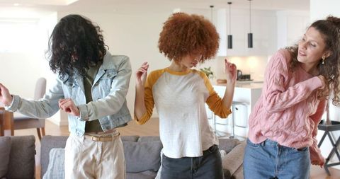 Diverse friends dancing in bright modern living room for casual home party lifestyle
