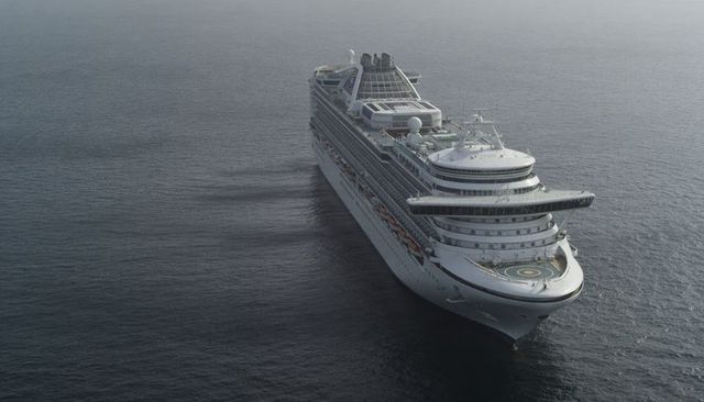 Gliding multideck cruise ship cutting through ocean showing helipad lifeboats balconies