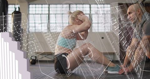 Woman doing sit-ups with trainer using ar fitness data in industrial gym