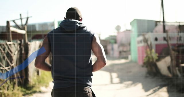 Person seen from behind jogging in an urban area with scattered buildings. Ideal for topics on fitness, jogging routes, general sports and lifestyle subjects. It conveys a sense of determination and a healthy lifestyle.