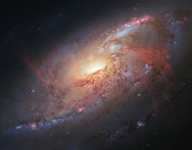This stunning depiction of galaxy M106 showcases its intricate spiral arms and unique hydrogen emissions. Ideal for educational resources on space exploration, astronomical presentations, or as a captivating background to emphasize the beauty of the cosmos. The image combines Hubble Space Telescope data with ground-based observations to create a detailed view of this magnificent galaxy.