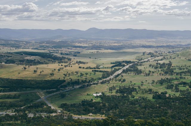 This scenic aerial street view captures wide and beautiful farmland set against mountains in the distance, ideal for promoting outdoor adventures, environmental campaigns, travel brochures, agricultural or countryside settings, and nature-centered publications.