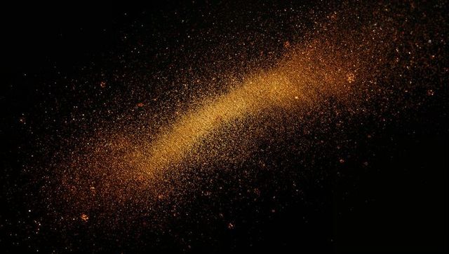 Dynamic swirling golden dust in dark space