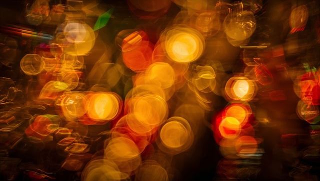 Warm golden bokeh orbs creating festive abstract glow with amber and red light halos