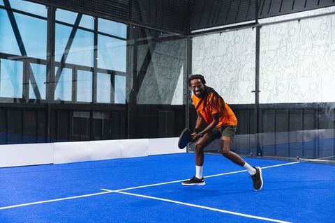 African American Male Athlete Playing Padel Tennis on Blue Court