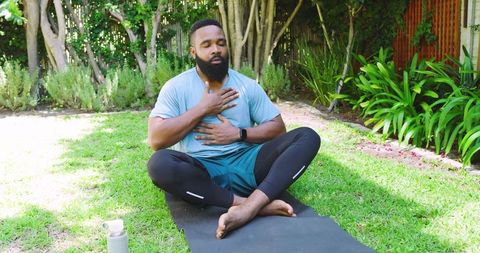 African American Man Meditating on Yoga Mat in Scenic Garden