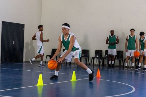 Teen Basketball Player Practicing Drills with Cones in Indoor Gym