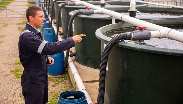 Technician inspecting industrial water tanks and pvc piping at outdoor facility