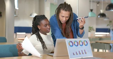 African American colleagues reviewing analytics on laptops in modern coworking office