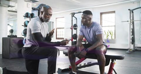 Personal trainer coaching client on bench and strength technique during gym session