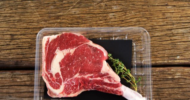 Raw Tomahawk Steak with Fresh Herbs on Wooden Table - Download Free Stock Images Pikwizard.com