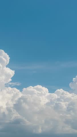Panning Vertical Sky Video Capturing Towering Cumulus Clouds Drifting Across Clear Blue Sky