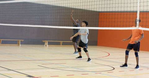 Multiracial men practicing indoor volleyball teamwork and training on hardwood gym court