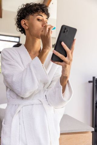Man Brushing Teeth and Using Smartphone in White Bathrobe